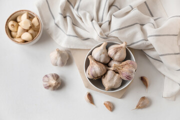 Bowls with fresh garlic and cloves on white background