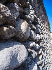 Close-up of rustic stone wall with blurred stones in background
