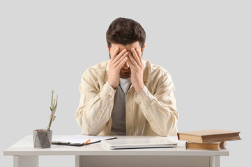 Portrait of worried man at table on light background