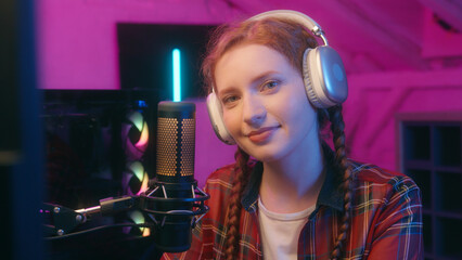 Caucasian woman teenager girl student female streamer blog cyber sport gaming addiction influencer blogger vlogger computer video game radio stream mic broadcast looking at camera smiling neon light