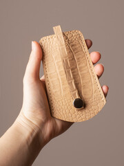 leather pocket key holder in hands on gray background
