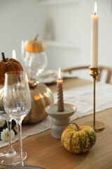 Stylish table setting with glasses, candles and autumn decor in dining room