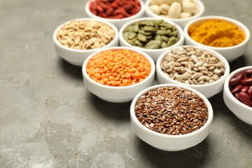 Different superfoods in bowls on grey table, closeup. Space for text