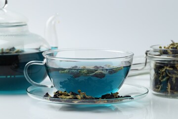 Fresh butterfly pea flower tea and dry petals on white table, closeup