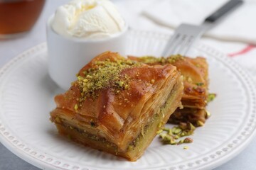 Delicious baklava with crushed nuts and ice cream on grey table, closeup