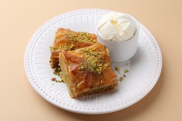 Delicious baklava with crushed nuts and ice cream on beige table, closeup