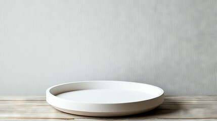  A white bowl rests atop a wooden table, adjacent to a white wall and set against a white backdrop