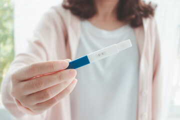 Happy pregnant woman holding a positive result pregnancy test with two stripes at home. Conception of a child. Family planning. wellness and healthy concept.