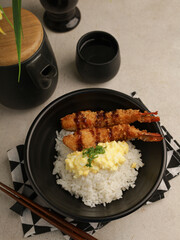 rice with fried shrimp and teriyaki sauce served with egg mayonnaise in black bowl