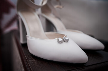 Elegant White High Heels with Sparkling Accessories on a Wooden Surface