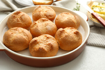 Baking dish with homemade tasty buns on light table, closeup