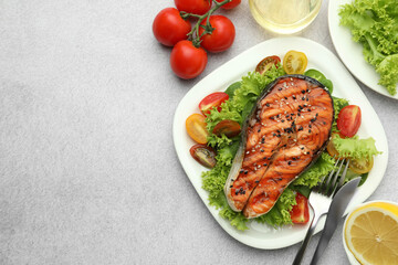 Tasty grilled salmon steak with vegetables served on light grey table, top view. Space for text