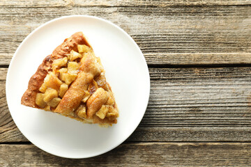 Slice of homemade apple pie on wooden table, top view. Space for text