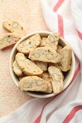 Traditional Italian almond biscuits (Cantucci) in bowl on beige textured table, top view