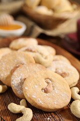 Tasty cashew cookies with powdered sugar on wooden board, closeup