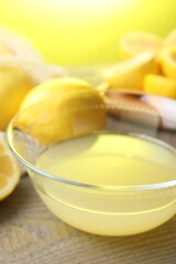 Bowl with fresh lemon juice and fruits on wooden table, closeup