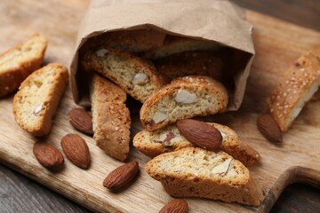 Paper bag with tasty almond biscuits (Cantuccini) and nuts on wooden table, closeup
