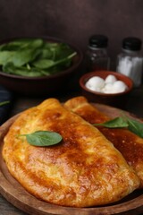 Tasty calzones with basil and mozzarella cheese on table, closeup