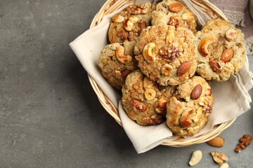 Tasty cookies with nuts in basket on grey table, top view. Space for text