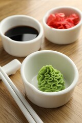 Hot wasabi paste, soy sauce, ginger and chopsticks on wooden table, closeup