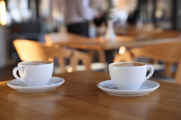 Cups of aromatic coffee on wooden table in cafe