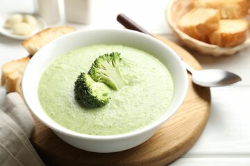 Delicious broccoli cream soup served on white wooden table, closeup