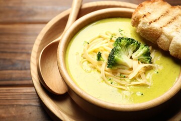 Delicious broccoli cream soup served on wooden table, closeup