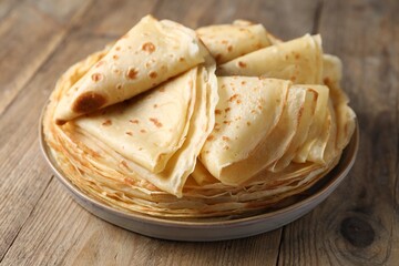 Delicious folded crepes on wooden table, closeup
