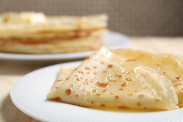 Tasty crepes with honey on wooden table, closeup
