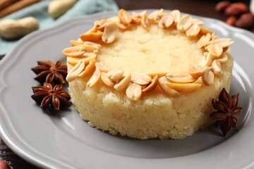 Delicious semolina halva with almond flakes and spices on table, closeup