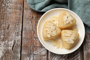 Pieces of delicious sweet semolina halva with almond flakes on wooden table, top view. Space for text