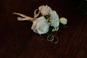 Elegant White Rose Boutonniere with Wedding Rings on Wooden Table