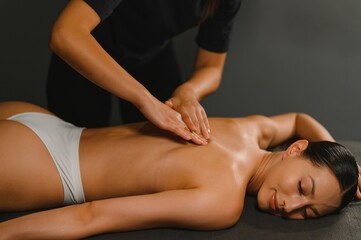 Fototapeta premium Body massage treatment. Woman having massage in the spa salon. Masseur working on his back