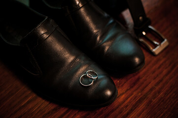 Elegant Wedding Rings Resting on Black Leather Shoes