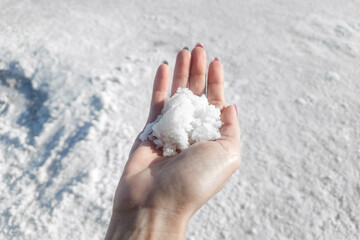 Woman hand holding snowflakes or salt frozen lake background. Global Warming Climate Change and Concept. end of the world. salt lake surface, dry salt lake