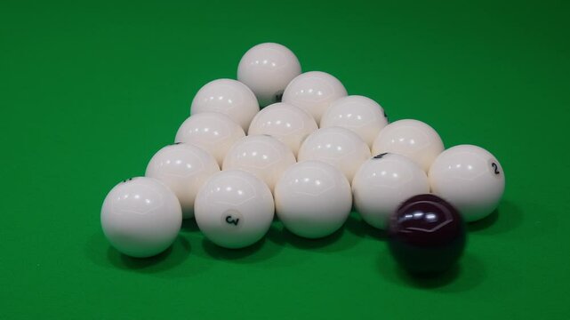 A neat arrangement of stacked pool balls sits on the classic green table, ready for play