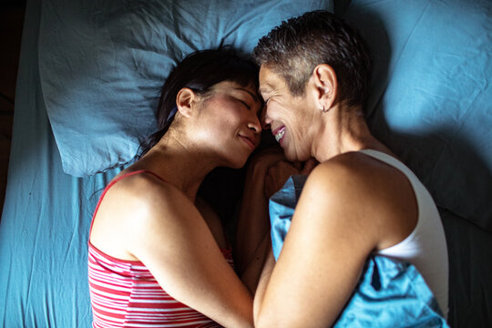 Lesbian couple embracing in bed at home