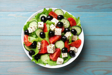 Delicious salad with feta cheese on light blue wooden table, top view