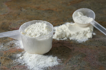 Protein powder and scoops on grey textured table