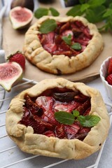 Tasty galettes with strawberries, figs and mint on light table, closeup