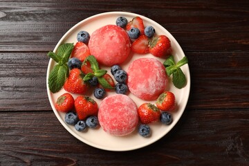 Delicious mochi, strawberries, blueberries and mint on wooden table, top view