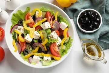 Delicious fresh Greek salad served on white tiled table, flat lay