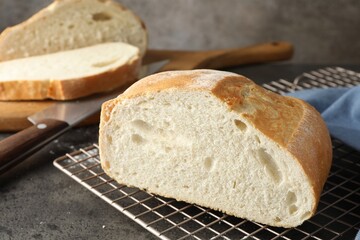 Cut fresh bread and knife on grey table, closeup