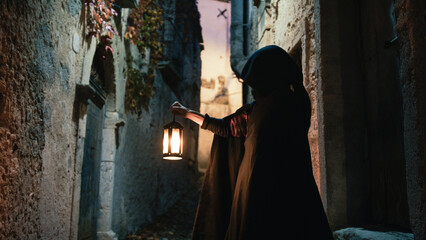 Naklejka premium Cloaked Man Holding The Lantern Through a Veil of Night
