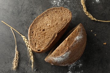 Halves of fresh bread and spikes on grey table, flat lay