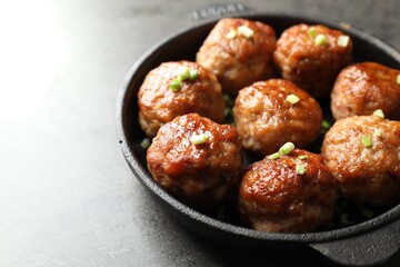 Tasty meatballs with green onion in baking dish on grey table, closeup
