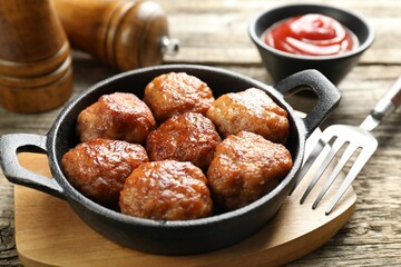 Tasty meatballs in baking dish served on wooden table, closeup