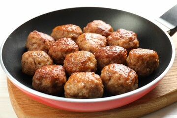 Tasty meatballs in frying pan on white table, closeup