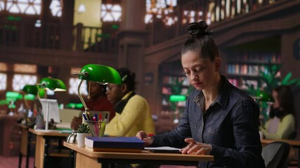 Noisy person disturbing people at the library by speaking very loud, being rude and answering a phone call in the study area. Disruptive annoying woman asked to keep silence. Camera B.