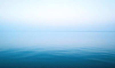 Obraz premium A serene view of calm water reflecting a soft, hazy sky.